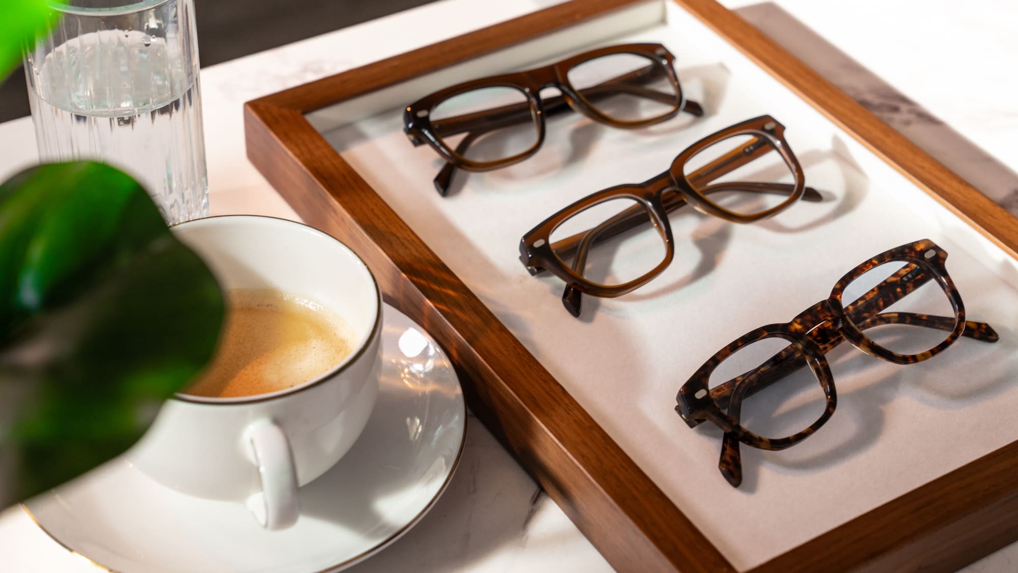Designer frames on a display tray beside a coffee