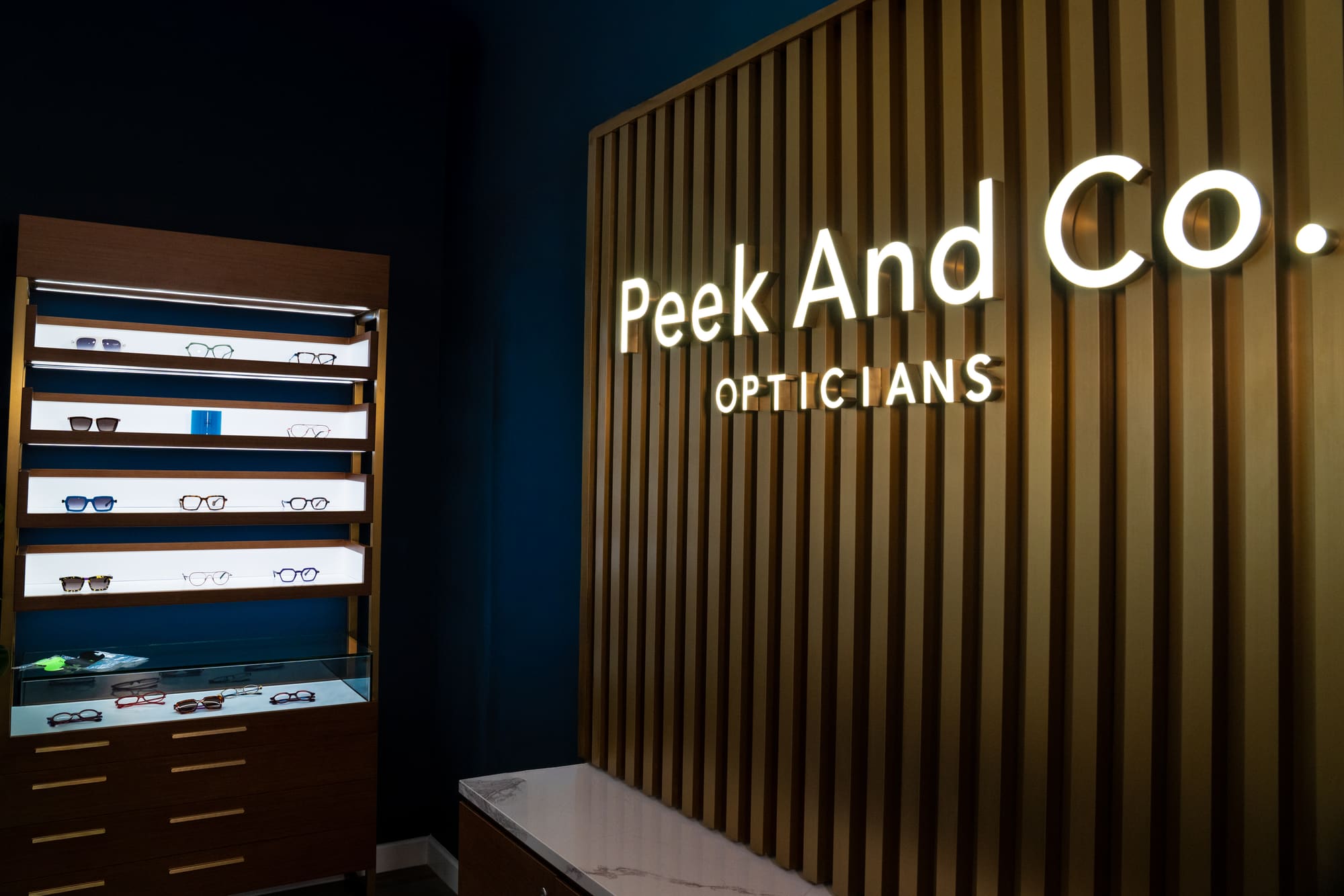 Peek And Co. Opticians sign beside a display of frames